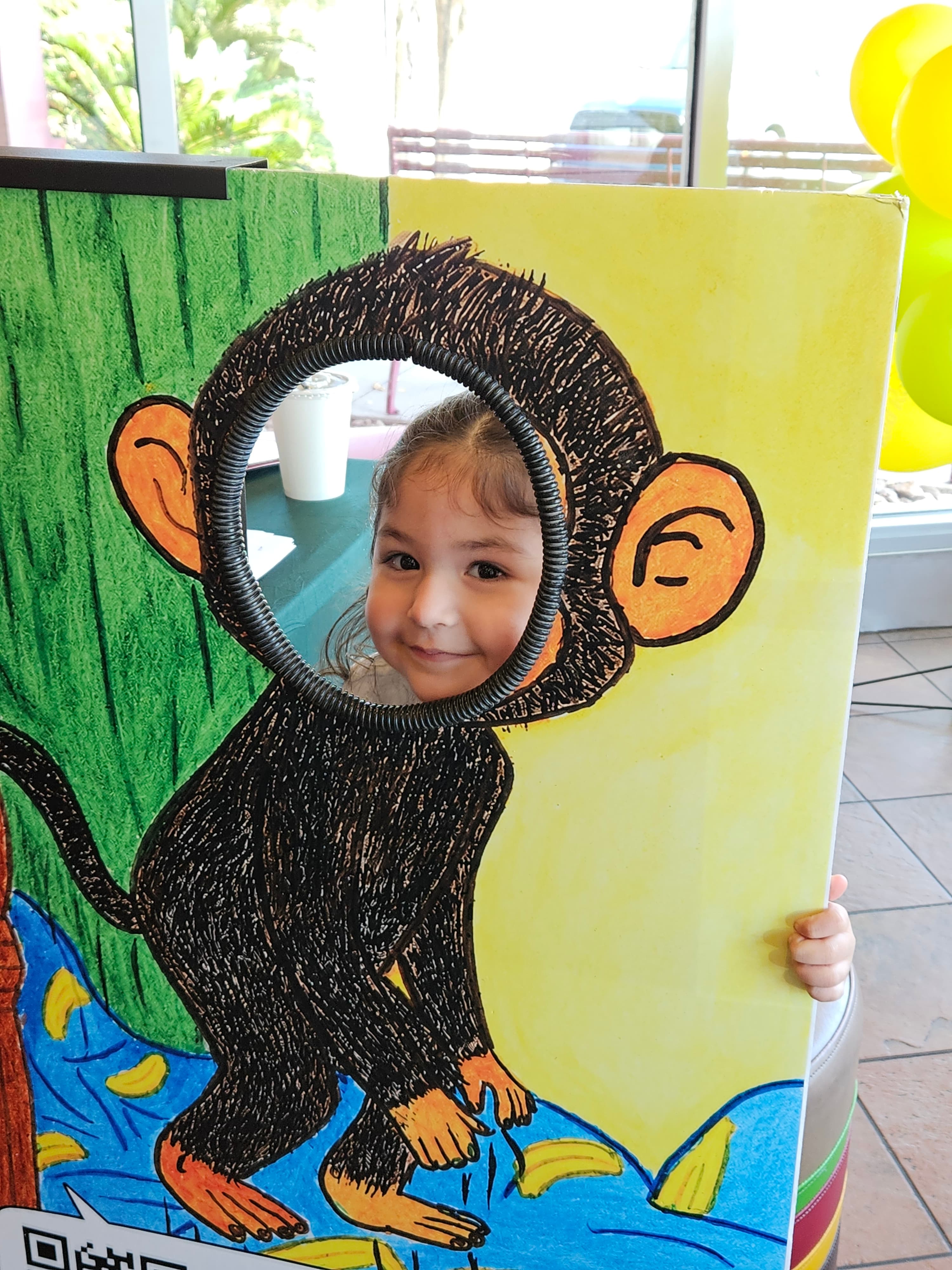 A smiling child poking their face through the Billy Monkey cutout