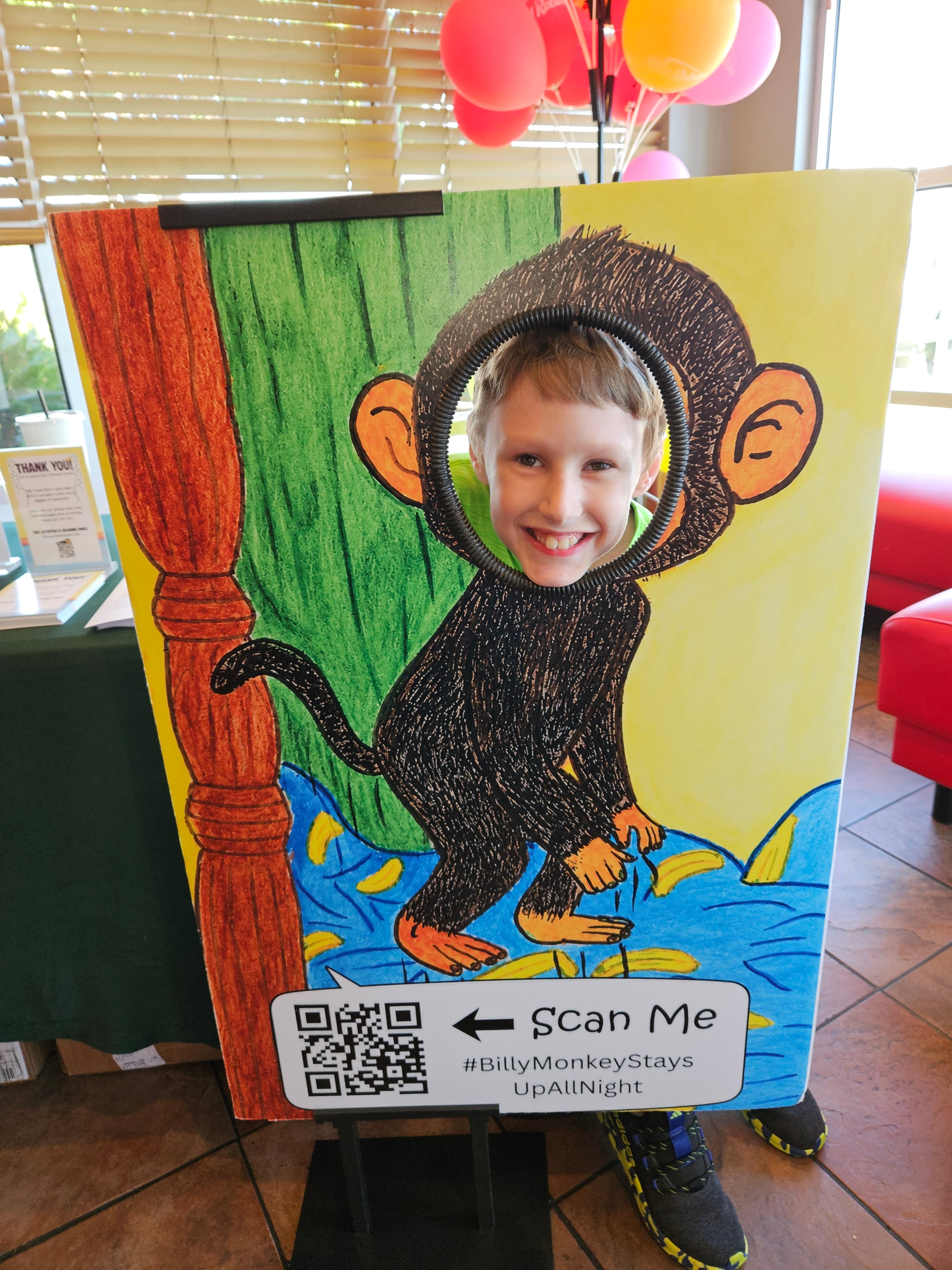 A boy grinning through the Billy Monkey face cutout